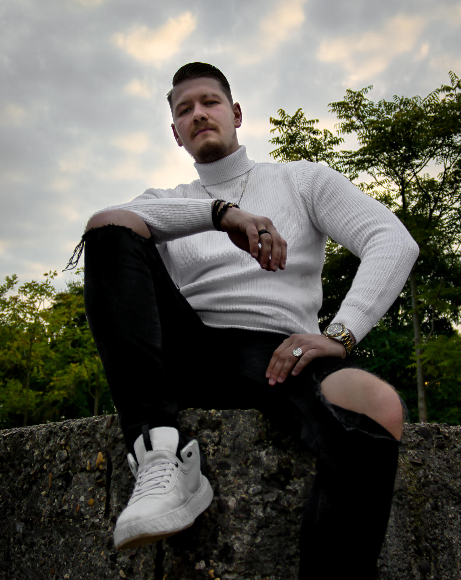 Mann sitzt auf Mauer portrait mann natürlich outdoor